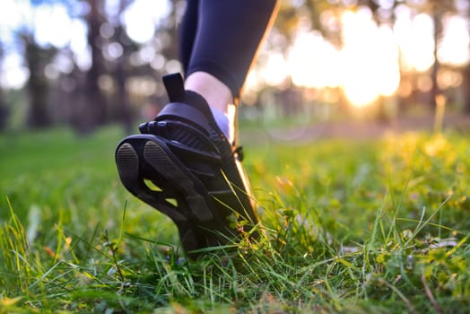 Close View Woman's feet in black sneakers walking on the grass in the woods