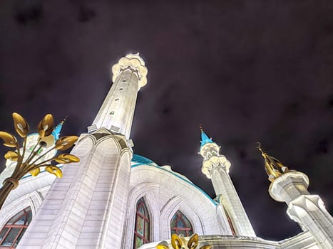 Beautiful white mosque with minarets against dark cloudy sky in night or evening. Ramadan Holiday