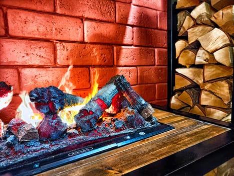 Fireplace. Firebrands, fire and a brick wall on the background. Firebrands ablaze with a cozy flame against a brick backdrop