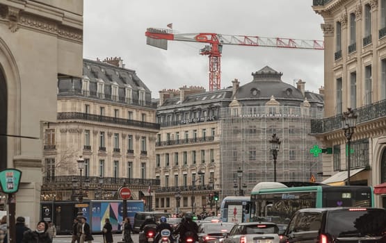 France, Paris - Jan 04, 2024 - Paris street view of Avenue de l Opera with traditional french building facades and construction crane, A fine building housing Royal Air Maroc and Berlitz near the Opera Garnier. Space for text, Selective focus.