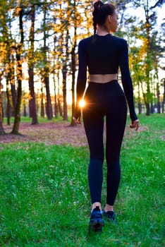 Shapely woman in black tight suit walking in nature in the woods in the sunlight. spring,summer