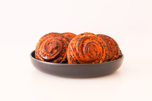 Sweet homemade cinnamon buns on a black ceramic plate.