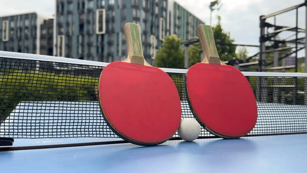 Rackets and ball on a blue tennis table - equipment for table tennis or ping pong. Old and new rackets close-up. Sports concept. . High quality photo