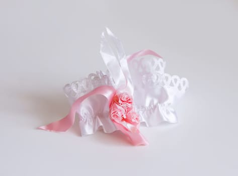 The bride's garter on a pink background. Wedding dress detail.