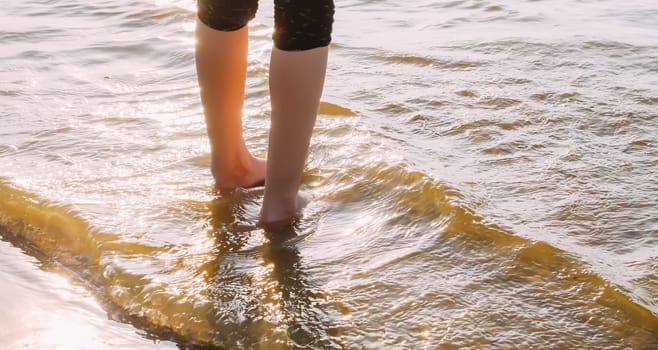 Child's bare feet walking at a beach.