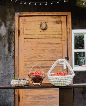 Red currant berries in a wicker basket on wooden door background in the village.