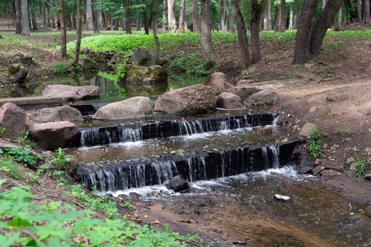 small artificial waterfall on a stream in a city park. Minsk, Belarus