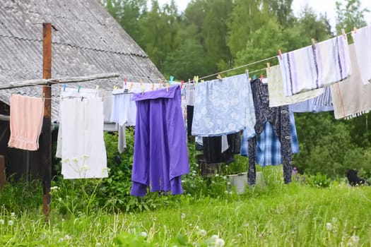 Different washed clothes hanging on a clothesline on rural yard.