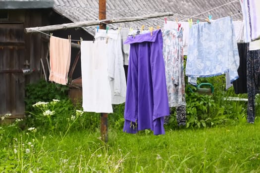 Different washed clothes hanging on a clothesline on rural yard.