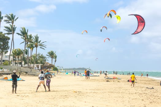 Crowd of active sporty people enjoying kitesurfing holidays and activities on perfect sunny day on Cabarete tropical sandy beach in Dominican Republic