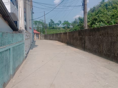 A concrete walkway with power lines and trees. High quality photo