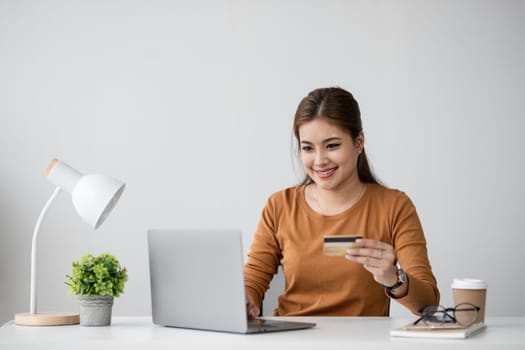 Happy young woman is shopping online and paying with credit card using online banking application..