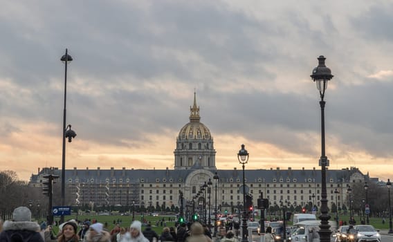 France, Paris - Jan 04, 2024 - The Hotel des Invalides commonly called Les Invalides (Baroque architecture style) containing The Army Museum (Musée de l'Armée) and monuments, all elating to the military history of France, as well as a hospital and an Old Soldiers' retirement home in Paris. Street lighs and traffic on road in the evening, Baroque architecture style, Space for text, Selective focus.