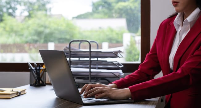 Senior accountant working on financial and marketing summary on laptop in office.