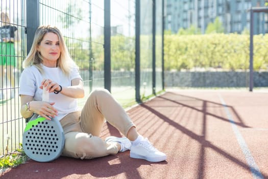 Happy female paddle tennis player during practice on outdoor court looking at camera. Copy space. High quality photo