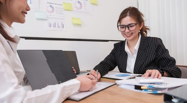 Young business woman and colleague are discussing company work documents..