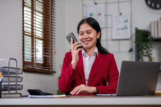 Beautiful accountant talking on the phone and calculating financial figures and calculating taxes for the company..