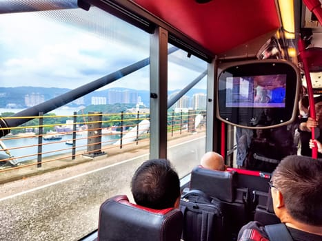 Hong Kong, China - April, 05, 2024: Travelers enjoy a ride on a Hong Kong double-decker bus with city views