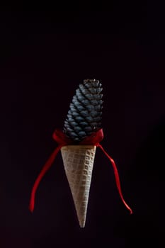 A cone of ice cream is suspended in the air with a red ribbon.