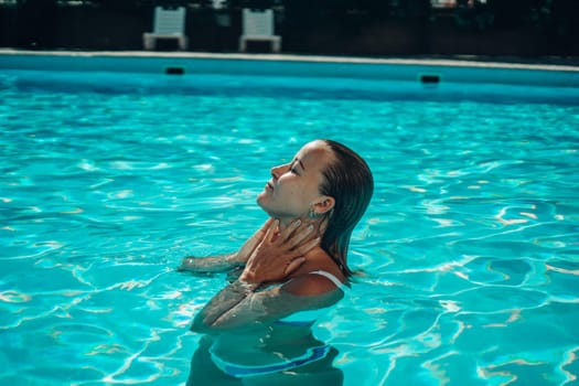 A woman is swimming in a pool. She is smiling and enjoying the water