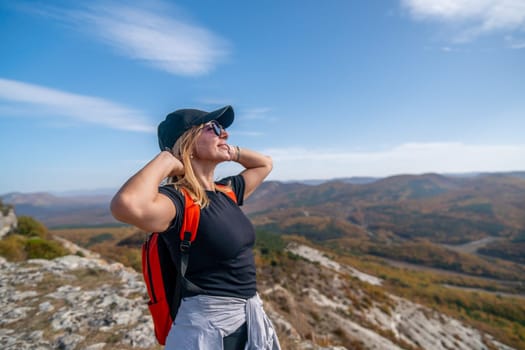 woman on mountain peak looking in beautiful mountain valley in autumn. Landscape with sporty young woman, blu sky in fall. Hiking. Nature.