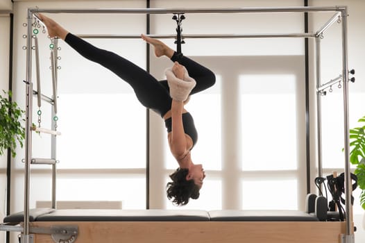 Asian woman doing aerial exercise on reformer machine