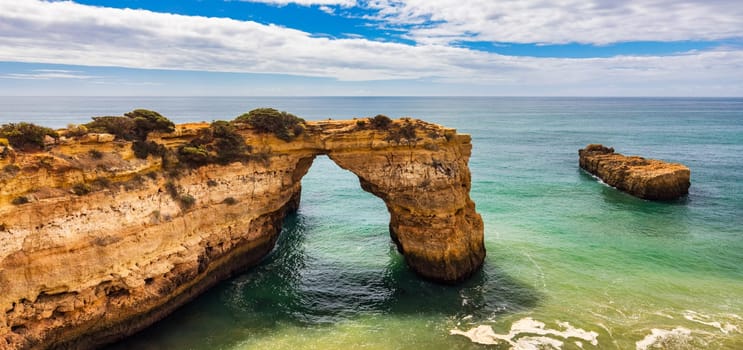 Natural arch above ocean, Arco de Albandeira, Algarve, Portugal. Stone arch at Praia de Albandeira, Lagoa, Algarve, Portugal. View of the natural arch Arco da Albandeira in the Algarve, Portugal.