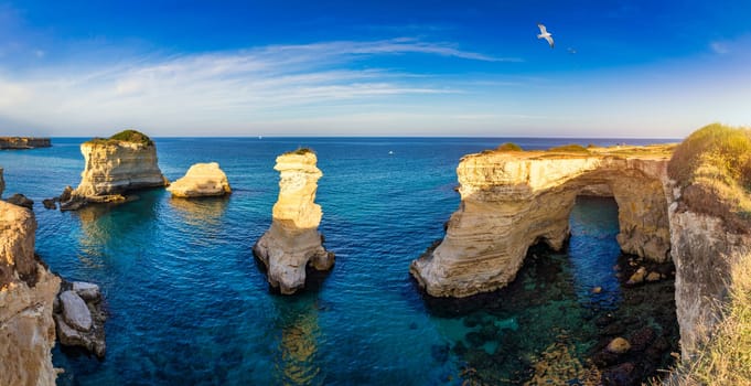 Stunning seascape with cliffs rocky arch and stacks (Faraglioni) at Torre Sant Andrea, Salento coast, Puglia region, Italy. Beautiful cliffs and sea stacks of Sant'Andrea, Salento, Apulia, Italy