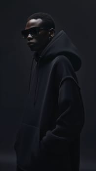 Photography: Fashionable african american man in black hoodie and sunglasses on dark background