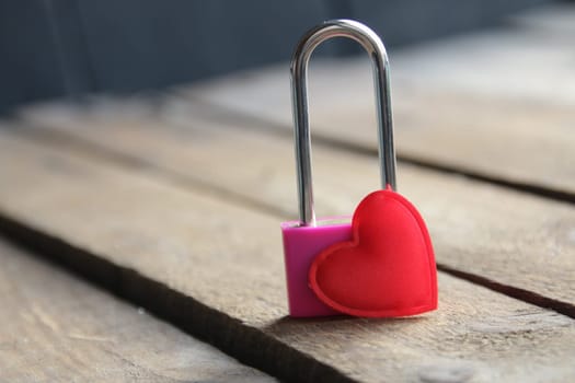 Padlock with a heart on a vintage wooden background.