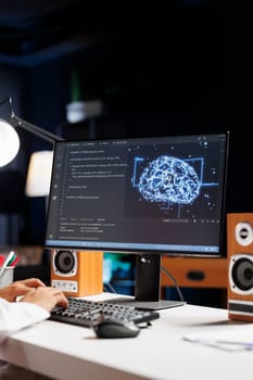 Selective focus of desktop PC showing a futuristic interface for Muslim guy to work on cybersecurity. Male person monitors a network and manages a supercomputer connected to a data center.