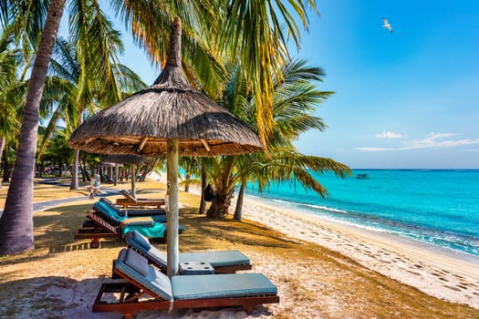 A beach with palm trees and umbrellas on Le morne Brabant beach in Mauriutius. Tropical crystal ocean with Le Morne beach and luxury beach in Mauritius. Le Morne beach with palm trees, white sand and luxury resorts, Mauritius.