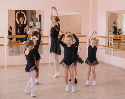 Children's ballet school. Caucasian woman teaching ballet to little girls