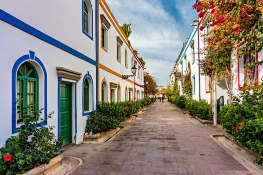 Street with blooming flowers in Puerto de Mogan, Gran Canaria, Spain. Favorite vacation place for tourists and locals on island. Puerto de Mogan with lots of bougainvillea flowers, Canary Island.