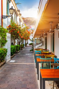 Street with blooming flowers in Puerto de Mogan, Gran Canaria, Spain. Favorite vacation place for tourists and locals on island. Puerto de Mogan with lots of bougainvillea flowers, Canary Island.