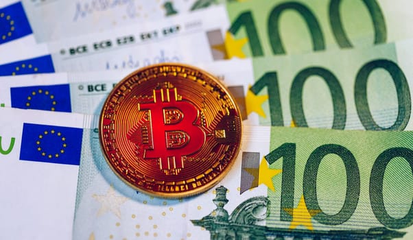 Golden bitcoin over Euro money. Bitcoin cryptocurrency. Crypto currency concept. Bitcoin with euro bills. Bitcoins stacked on euro banknotes.