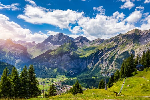 Panoramic view of idyllic mountain scenery in the Alps with fresh green meadows in bloom on a beautiful sunny day in summer, Switzerland. Idyllic mountain landscape in the Alps with meadows in summer.