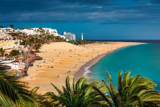 Aerial view of beach in Morro del Jable town (Morro Jable beach) on Fuerteventura island, Canary Islands, Spain. One of the best beach in the Canaries. Motorral lighthouse in distance.