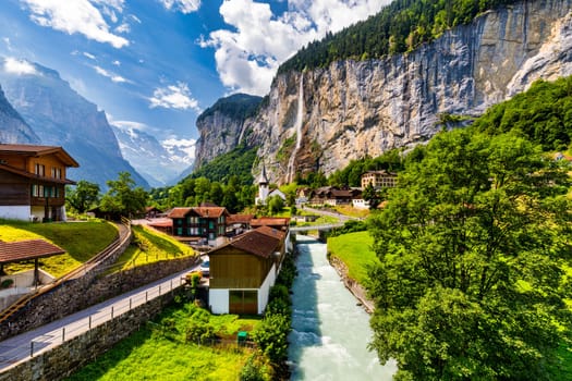 Amazing summer landscape of touristic alpine village Lauterbrunnen with famous church and Staubbach waterfall. Location: Lauterbrunnen village, Berner Oberland, Switzerland, Europe.