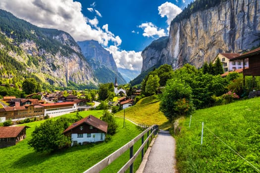 Amazing summer landscape of touristic alpine village Lauterbrunnen with famous church and Staubbach waterfall. Location: Lauterbrunnen village, Berner Oberland, Switzerland, Europe.