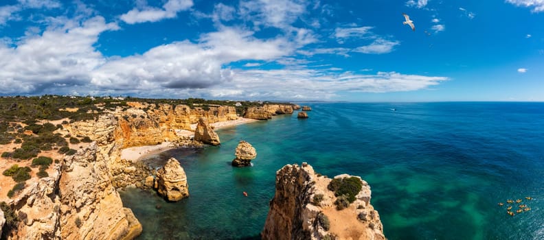 Praia da Marinha, beautiful beach Marinha in Algarve, Portugal. Navy Beach (Praia da Marinha) with flying seagulls over the beach, located on the Atlantic coast in Lagoa Municipality, Algarve.