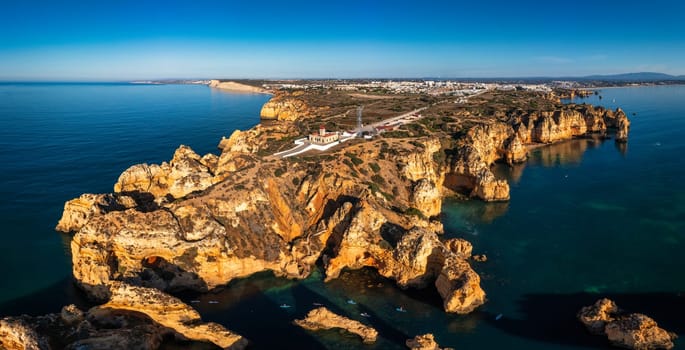 Panoramic view, Ponta da Piedade near Lagos in Algarve, Portugal. Cliff rocks and tourist boat on sea at Ponta da Piedade, Algarve region, Portugal. Ponta da Piedade, Algarve region, Portugal.