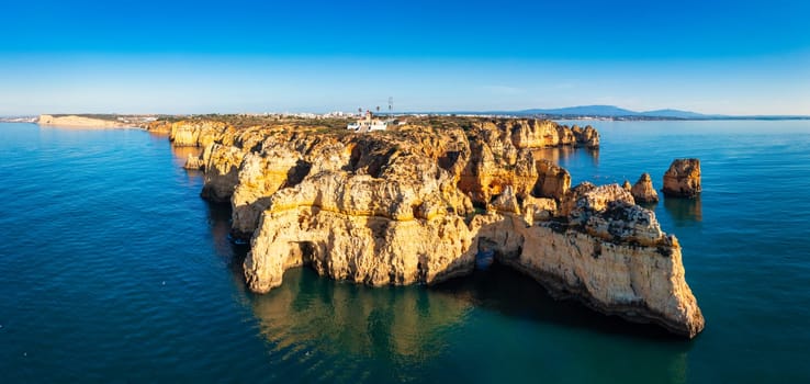 Panoramic view, Ponta da Piedade near Lagos in Algarve, Portugal. Cliff rocks and tourist boat on sea at Ponta da Piedade, Algarve region, Portugal. Ponta da Piedade, Algarve region, Portugal.