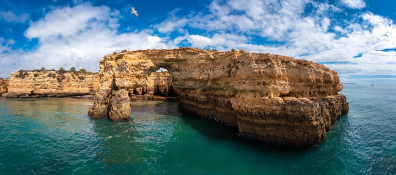 Natural arch above ocean, Arco de Albandeira, Algarve, Portugal. Stone arch at Praia de Albandeira, Lagoa, Algarve, Portugal. View of the natural arch Arco da Albandeira in the Algarve, Portugal.