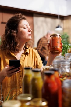 Healthy living woman in zero waste store using smartphone notes app to check shopping list. Meticulous customer looking to replenish pantry at home with natural pesticides free food essentials