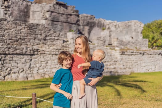 Mother and two sons tourists enjoying the view Pre-Columbian Mayan walled city of Tulum, Quintana Roo, Mexico, North America, Tulum, Mexico. El Castillo - castle the Mayan city of Tulum main temple.