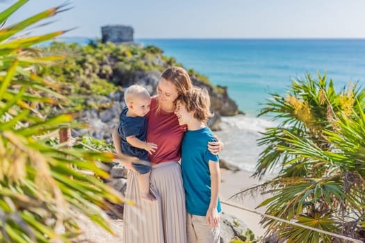 Mother and two sons tourists enjoying the view Pre-Columbian Mayan walled city of Tulum, Quintana Roo, Mexico, North America, Tulum, Mexico. El Castillo - castle the Mayan city of Tulum main temple.