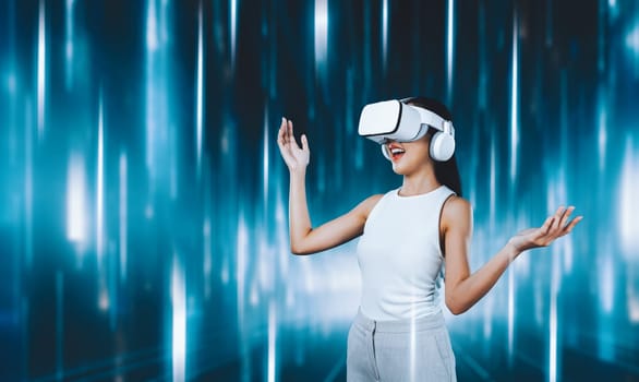 Female standing and wearing white VR headset and white sleeveless connect metaverse, future technology creating cyberspace community. She enjoy looking fantasy light around her. Hallucination.