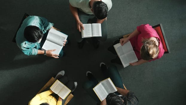 Top down view of prayer reading at bible book and sitting in circle with bible book on laps. Aerial view of diverse people looking at book while studying with faith, trust and hope, calm. Symposium.