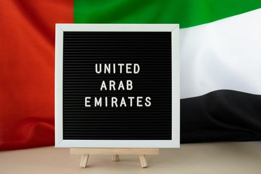 Text UNITED ARAB EMIRATES on background waving flag of UAE. National holiday, Independence Commemoration Day Muslim, congratulations. Arabian holidays. Advertisement of Dubai celebration